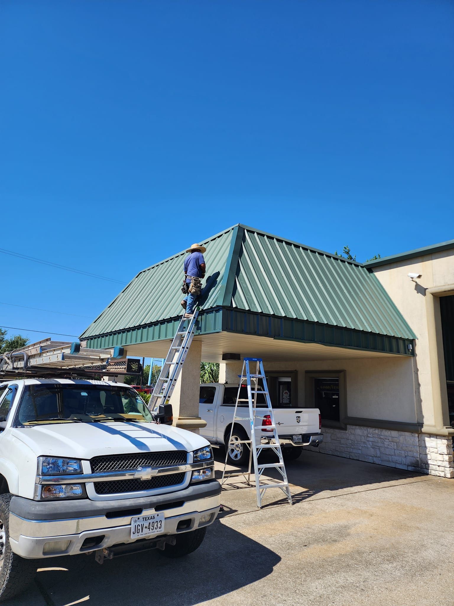 A man is standing on a ladder on the roof of a building.