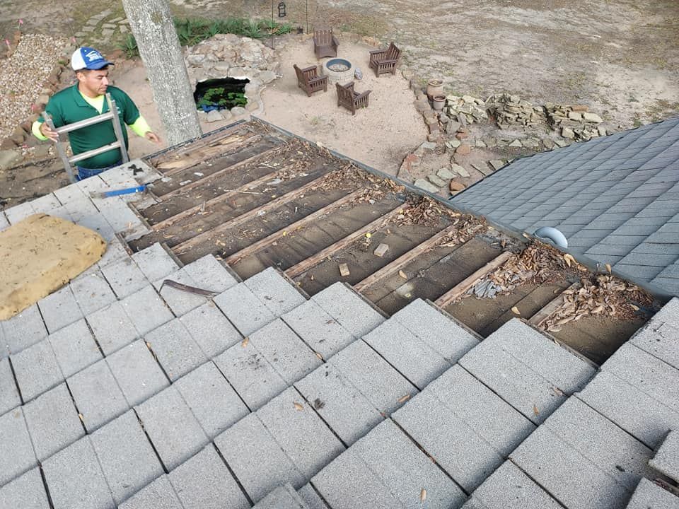 A man is standing on top of a roof with a ladder.