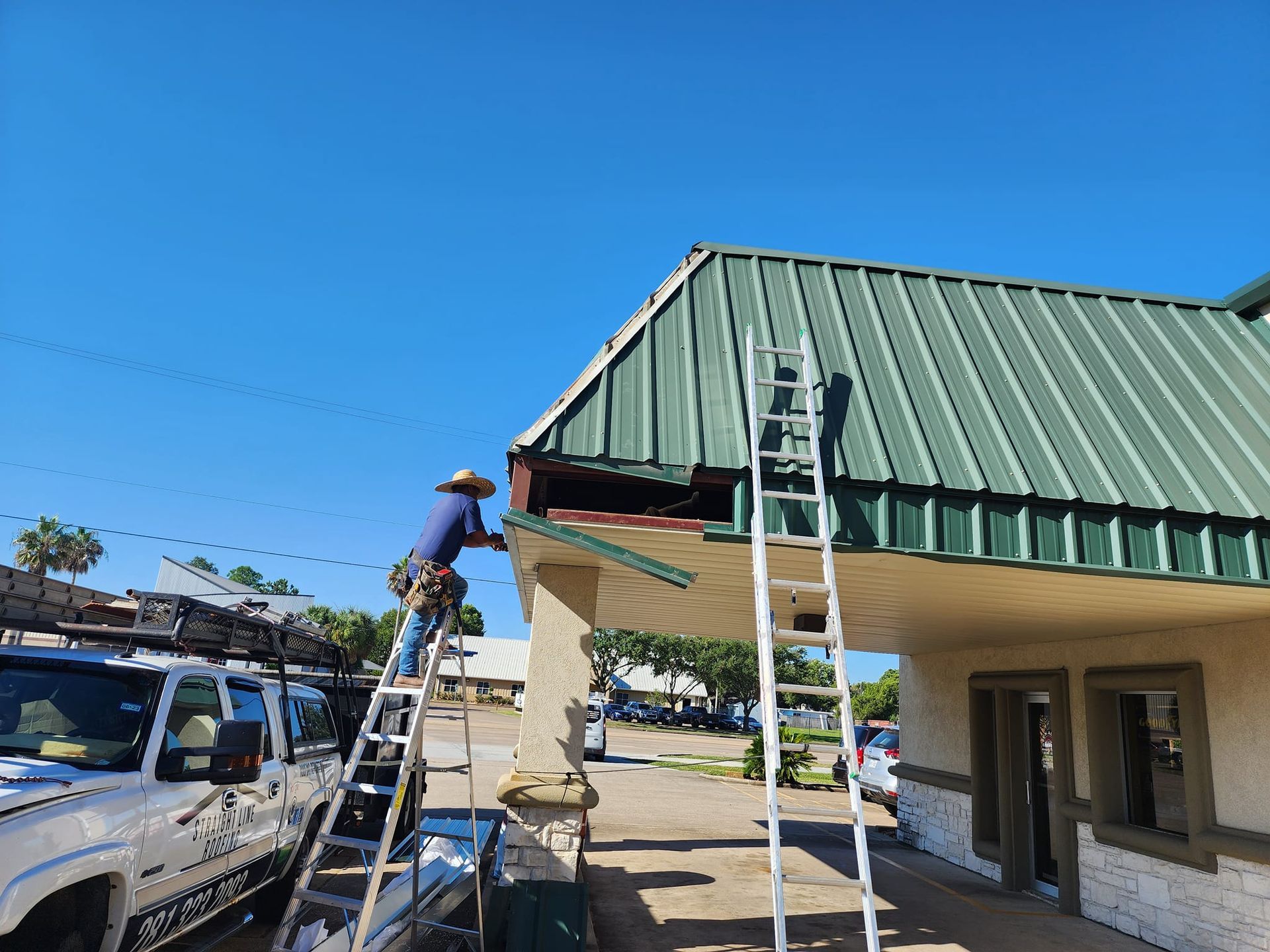 A man on a ladder is working on the roof of a building.