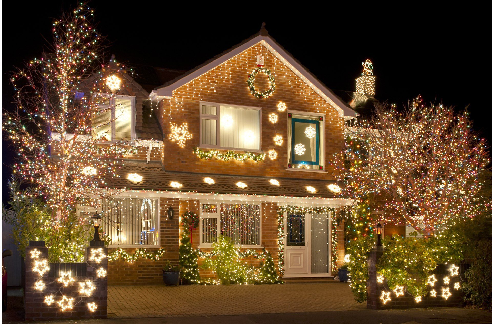 A house is decorated with christmas lights and trees