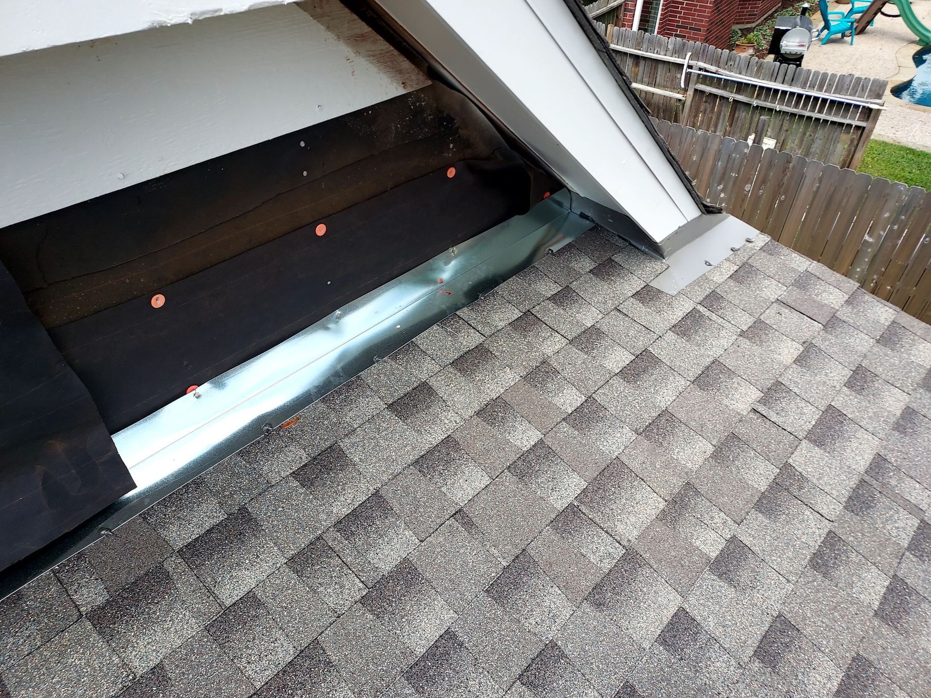 A close up of a roof with shingles and a window.