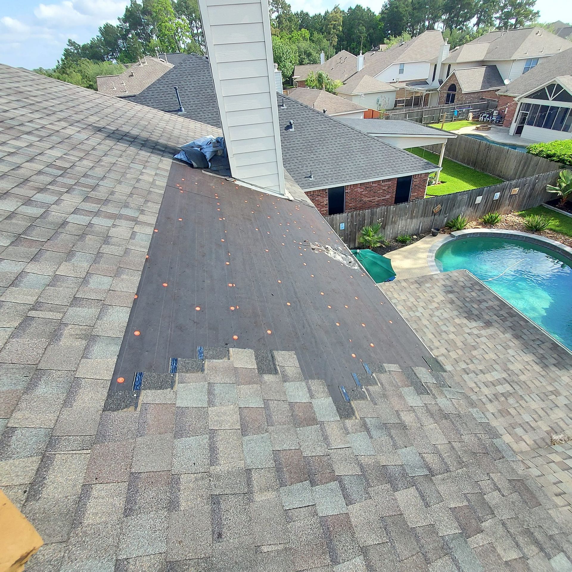 A roof with a chimney and a pool in the backyard
