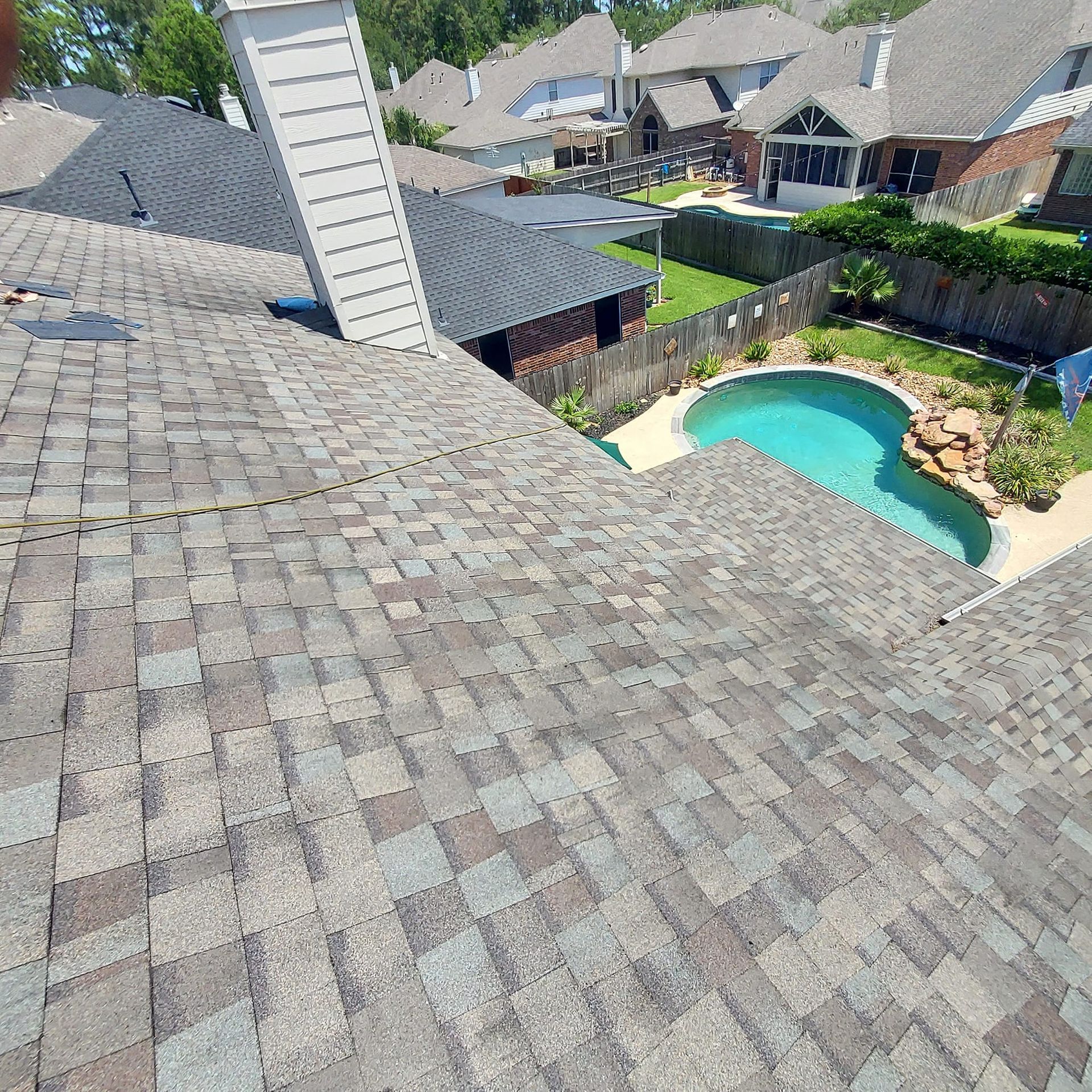 An aerial view of a roof with a pool in the backyard