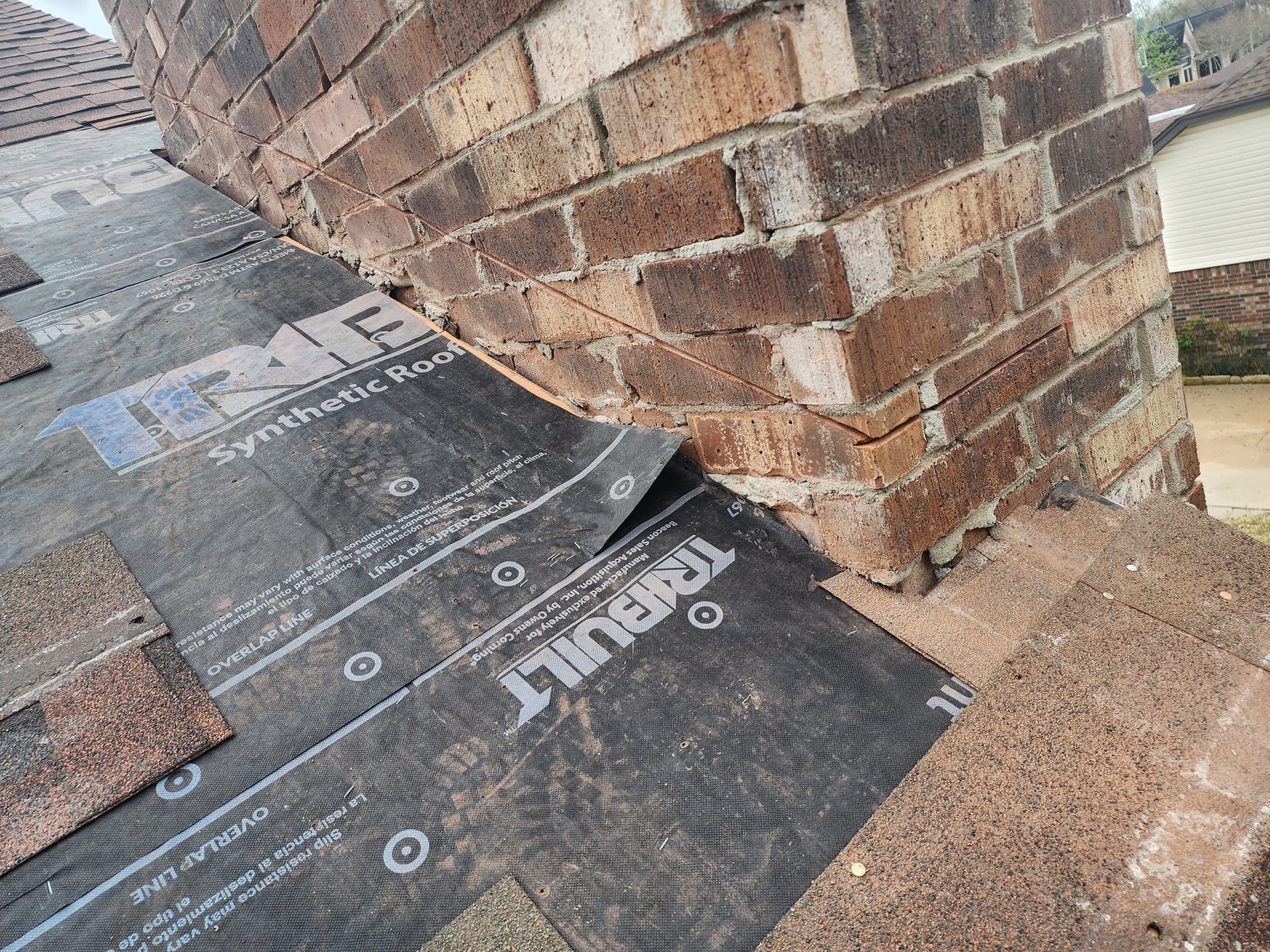 A piece of roofing material is sitting on top of a brick wall.