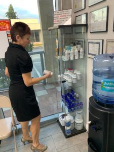 A woman in a black dress is standing in front of a glass display case.