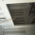 A person is working on a ceiling with a screwdriver.