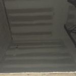 A close up of a black tile floor with a reflection of a person standing on it.