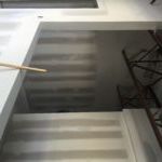 A close up of a staircase with a chair in the background.