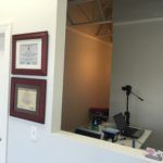 A room with two framed pictures on the wall and a laptop on a desk.