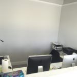 A desk with a computer and a printer in an office.