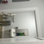 A bathroom with a toilet , sink and mirror.