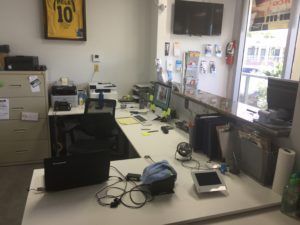 A desk with a laptop and a tablet on it in an office.