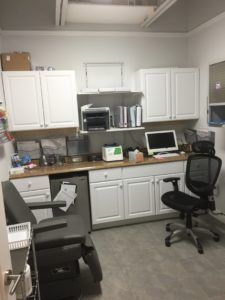 A room with white cabinets and a black chair