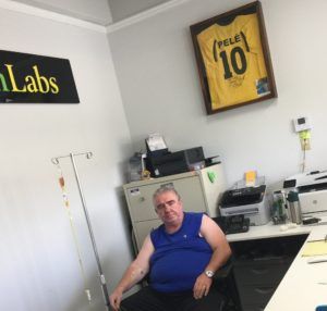 A man is sitting at a desk in front of a sign that says labs