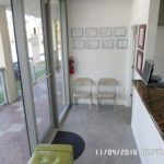 A waiting room in a dental office with chairs and a green ottoman.