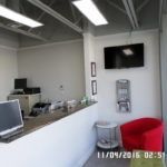 A waiting room with a red chair and a computer on the counter.