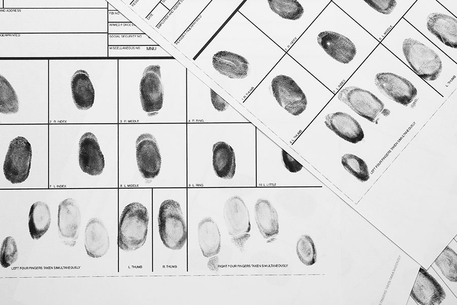 A bunch of fingerprint sheets are laying on top of each other on a table.