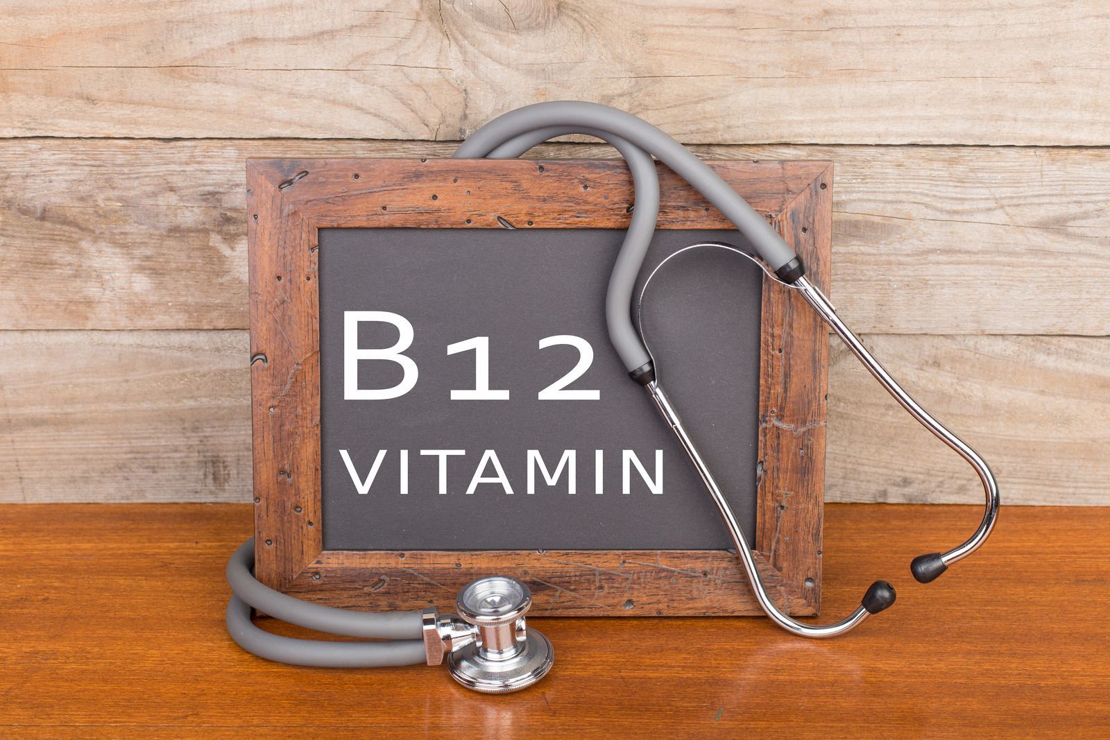 A chalkboard with the words b12 vitamin and a stethoscope on a wooden table.