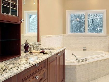 A bathroom with a tub , sink , mirror and window.