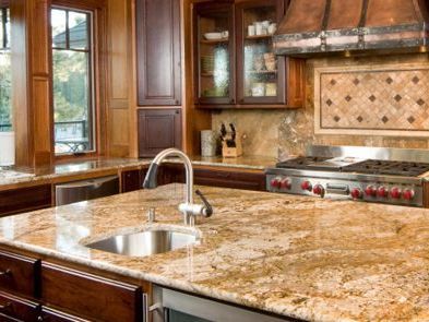 A kitchen with granite counter tops , stainless steel appliances , a sink , and a stove.