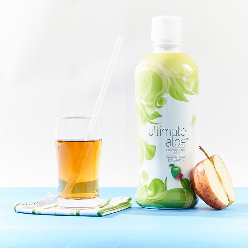 A bottle of ultimate aloe next to a glass of juice