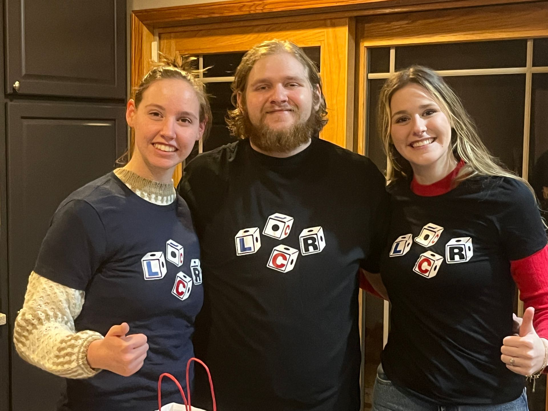 A man and two women are posing for a picture in a kitchen.