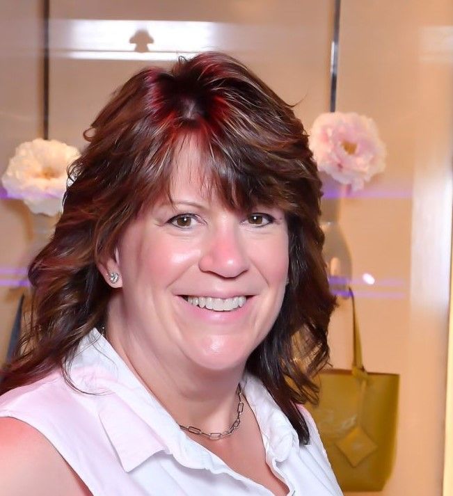 A woman with long brown hair is smiling for the camera