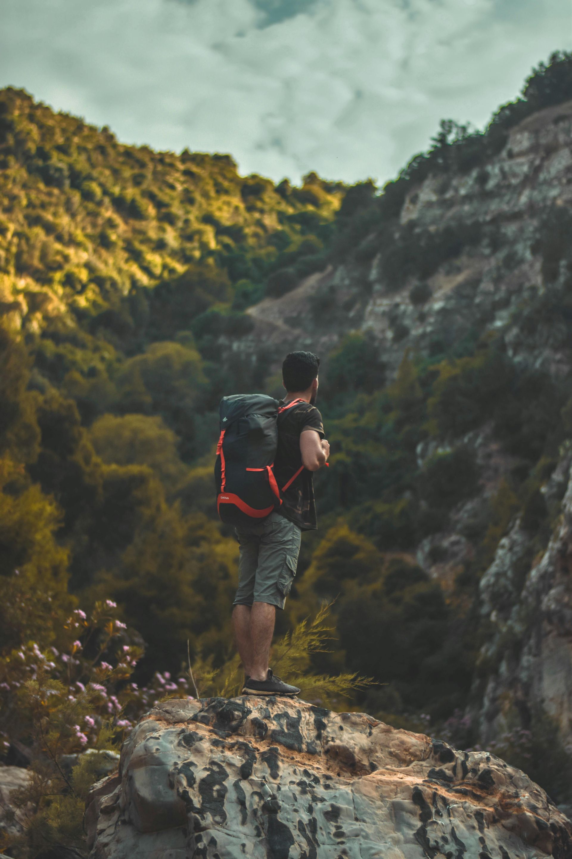 A man with a backpack is standing on top of a mountain.