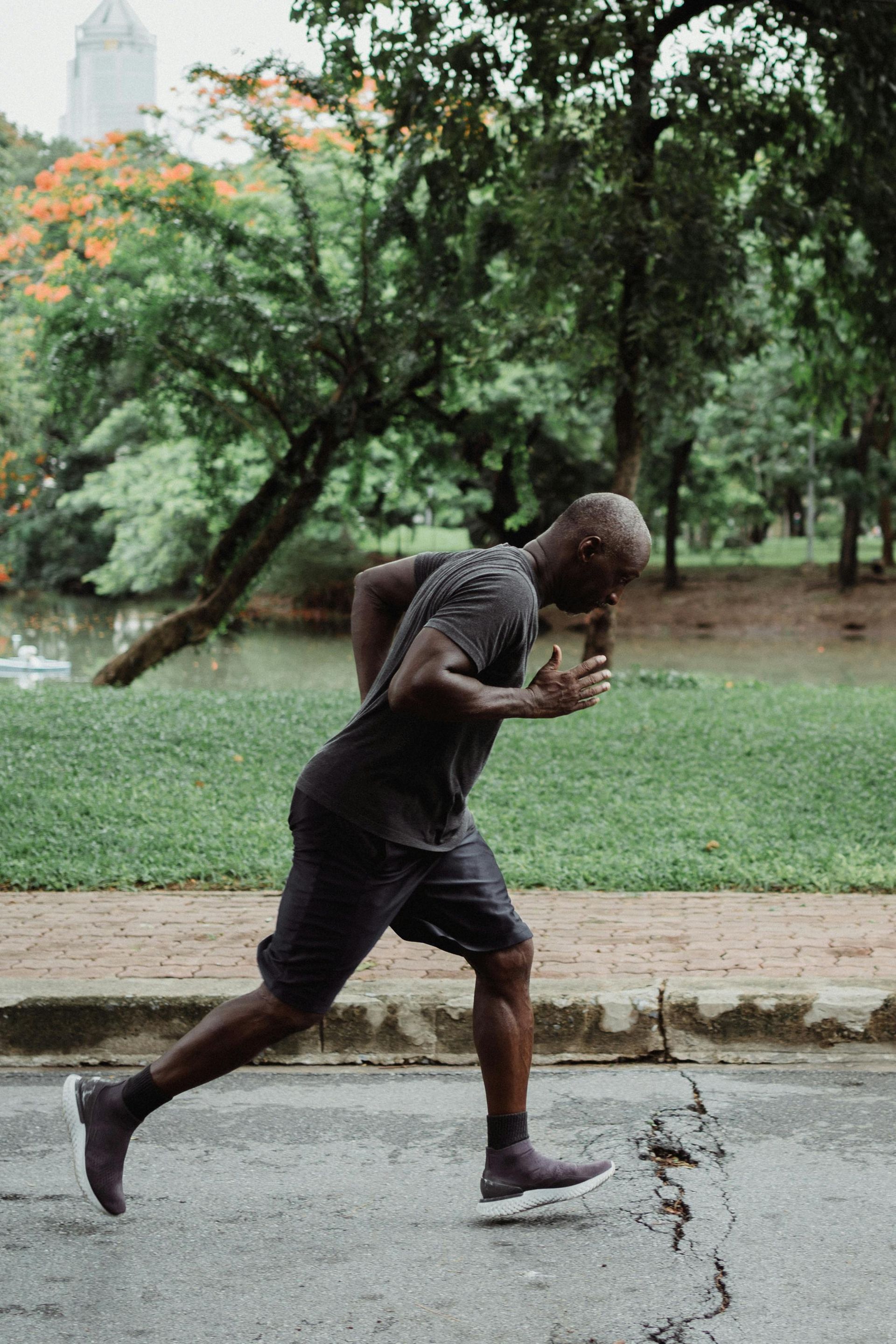 A man is running down a street in a park.