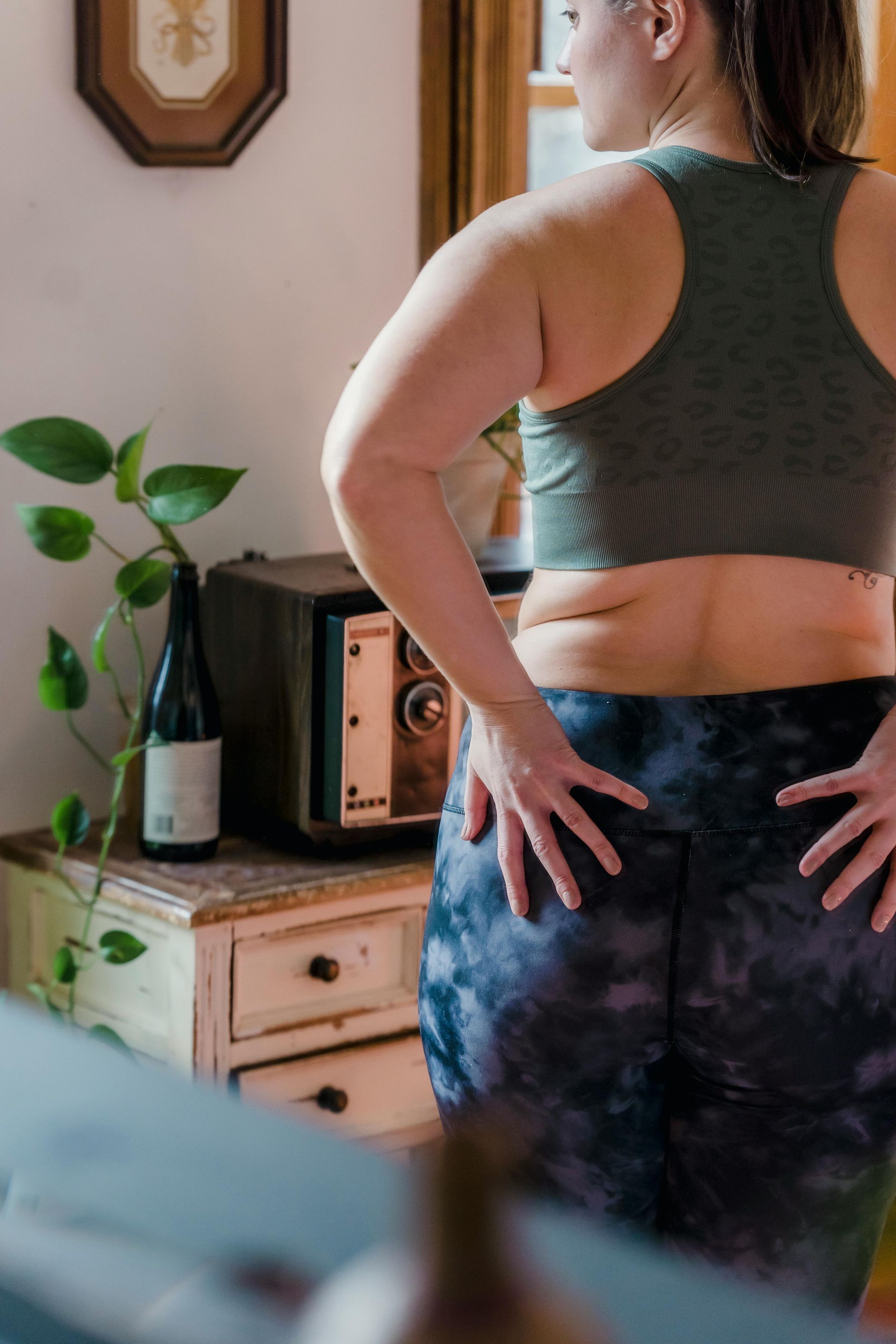 A woman is standing in front of a mirror with her hands on her hips.
