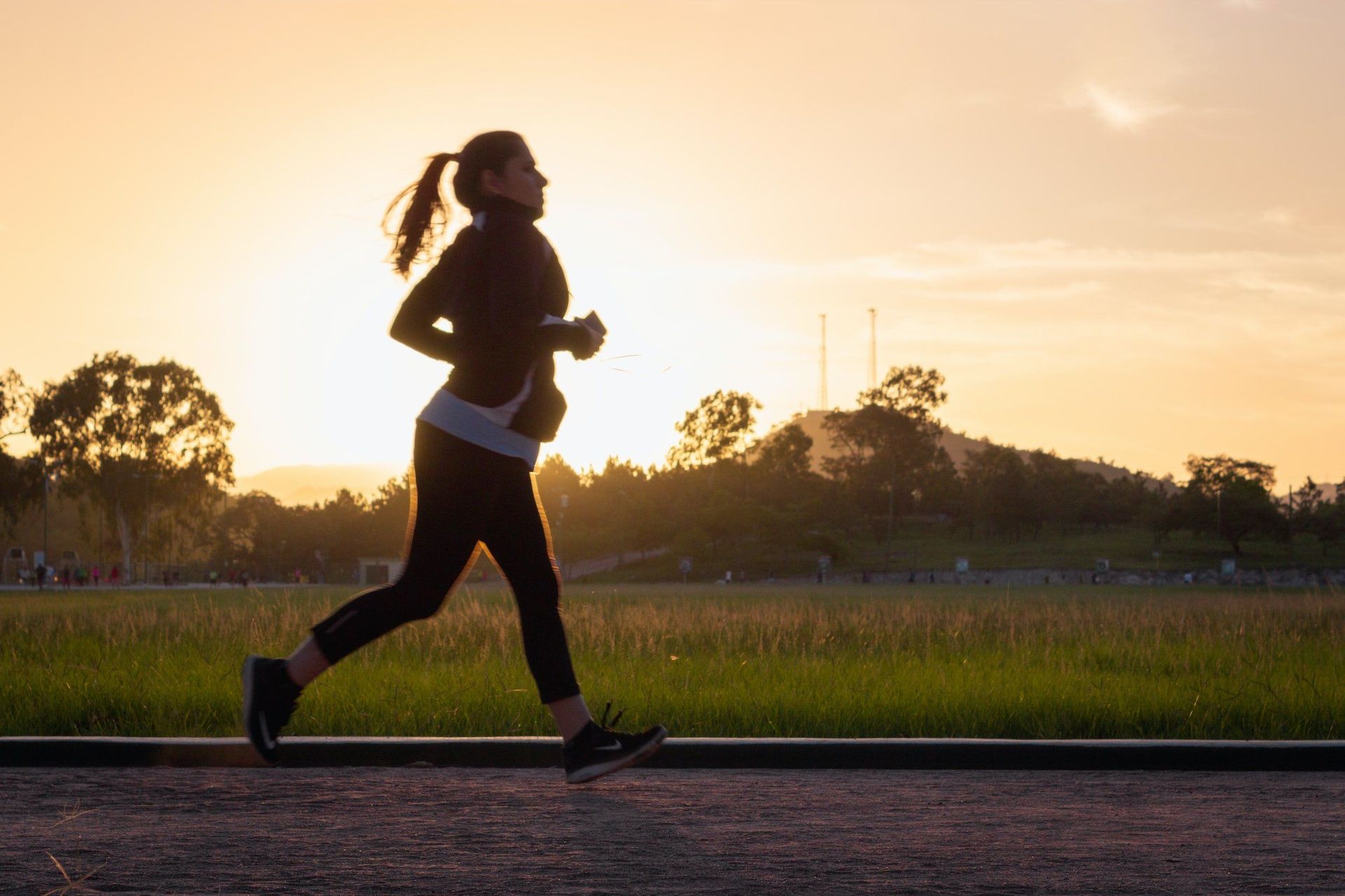 A woman is running on a road at sunset.