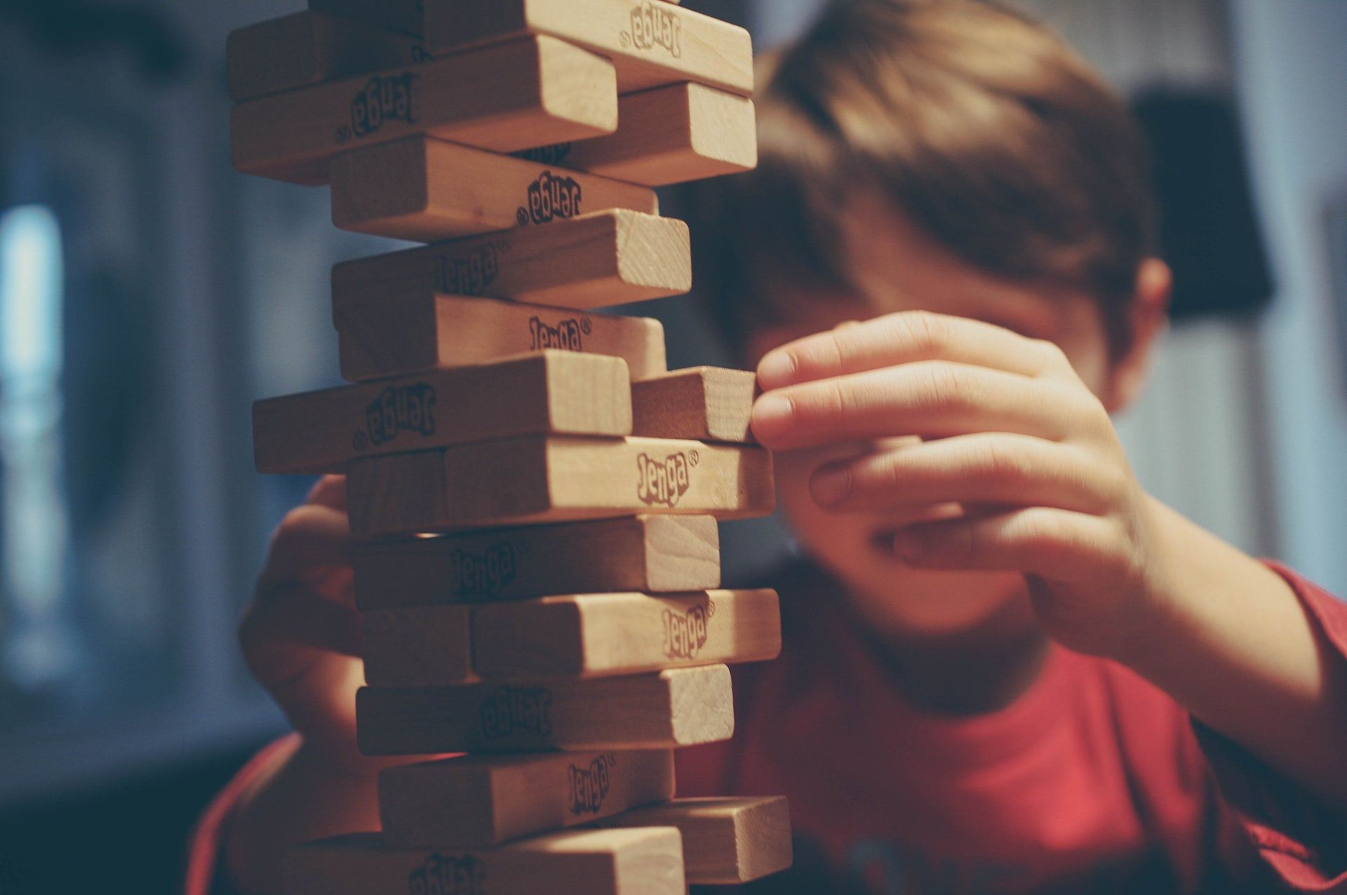 A young boy is playing a game of jenga with wooden blocks.