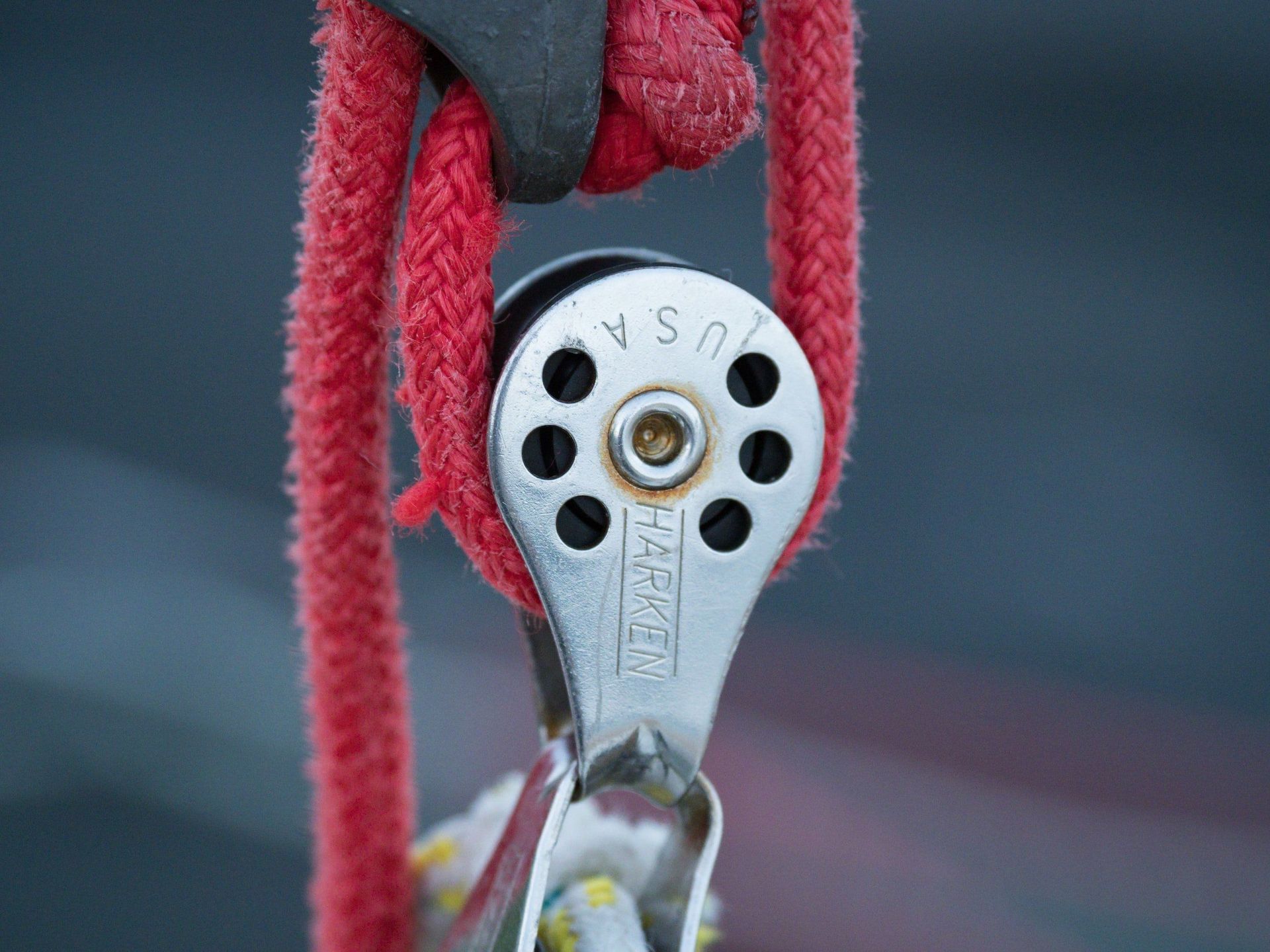 A close up of a pulley with a red rope attached to it.
