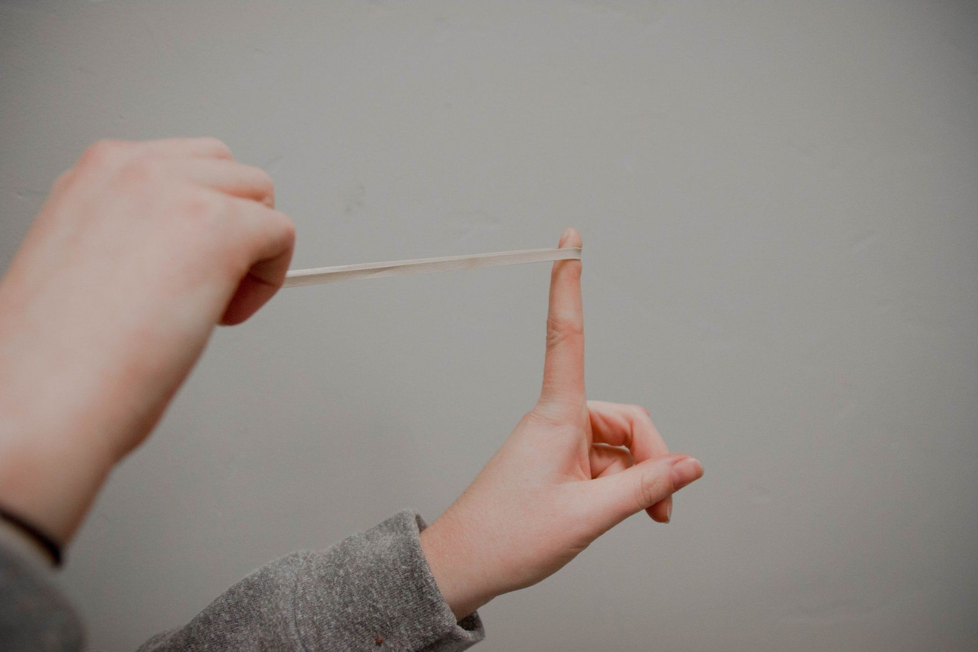 A person is holding a piece of string between their fingers.