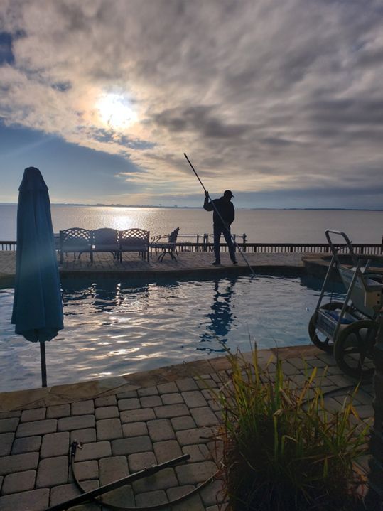 Worker Cleaning the Pool on a Cloudy Day