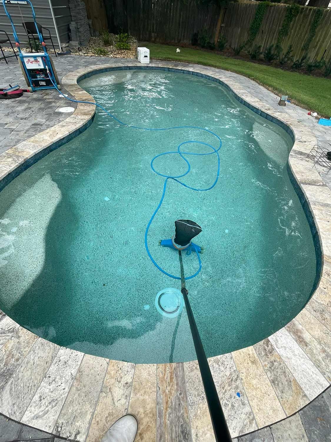 Worker Cleaning the Pool Using a Vacuum