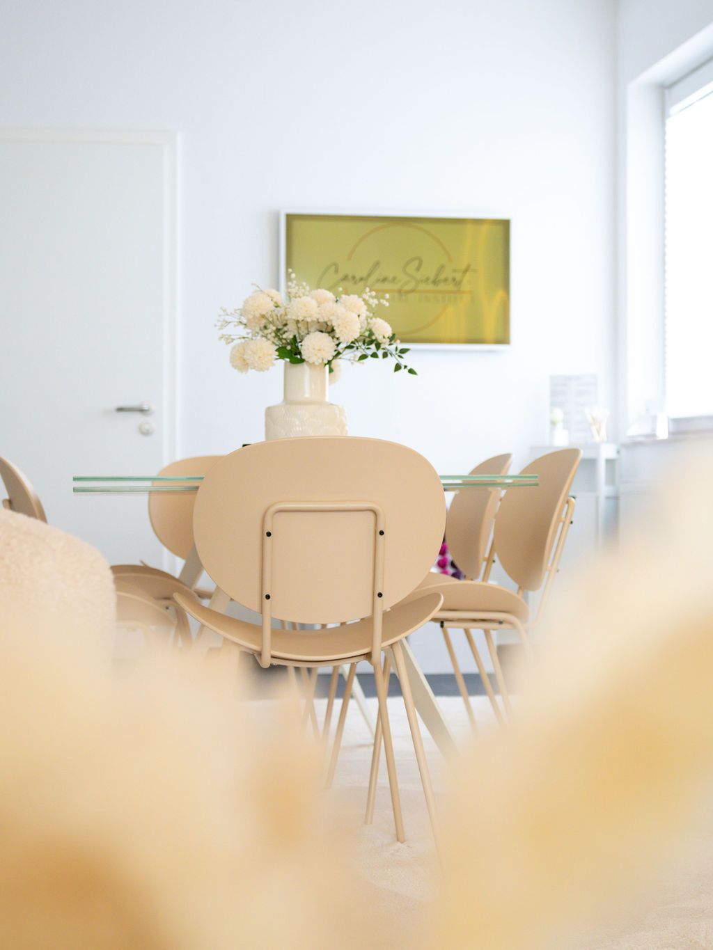 Ein Esszimmer mit einem Tisch und Stühlen und einer Vase mit Blumen auf dem Tisch.