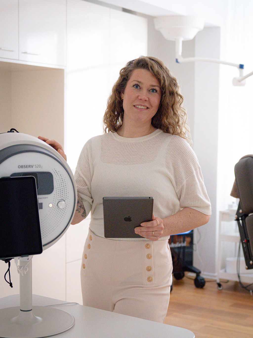 Eine Frau steht mit einem Tablet in der Hand vor einem Gerät.