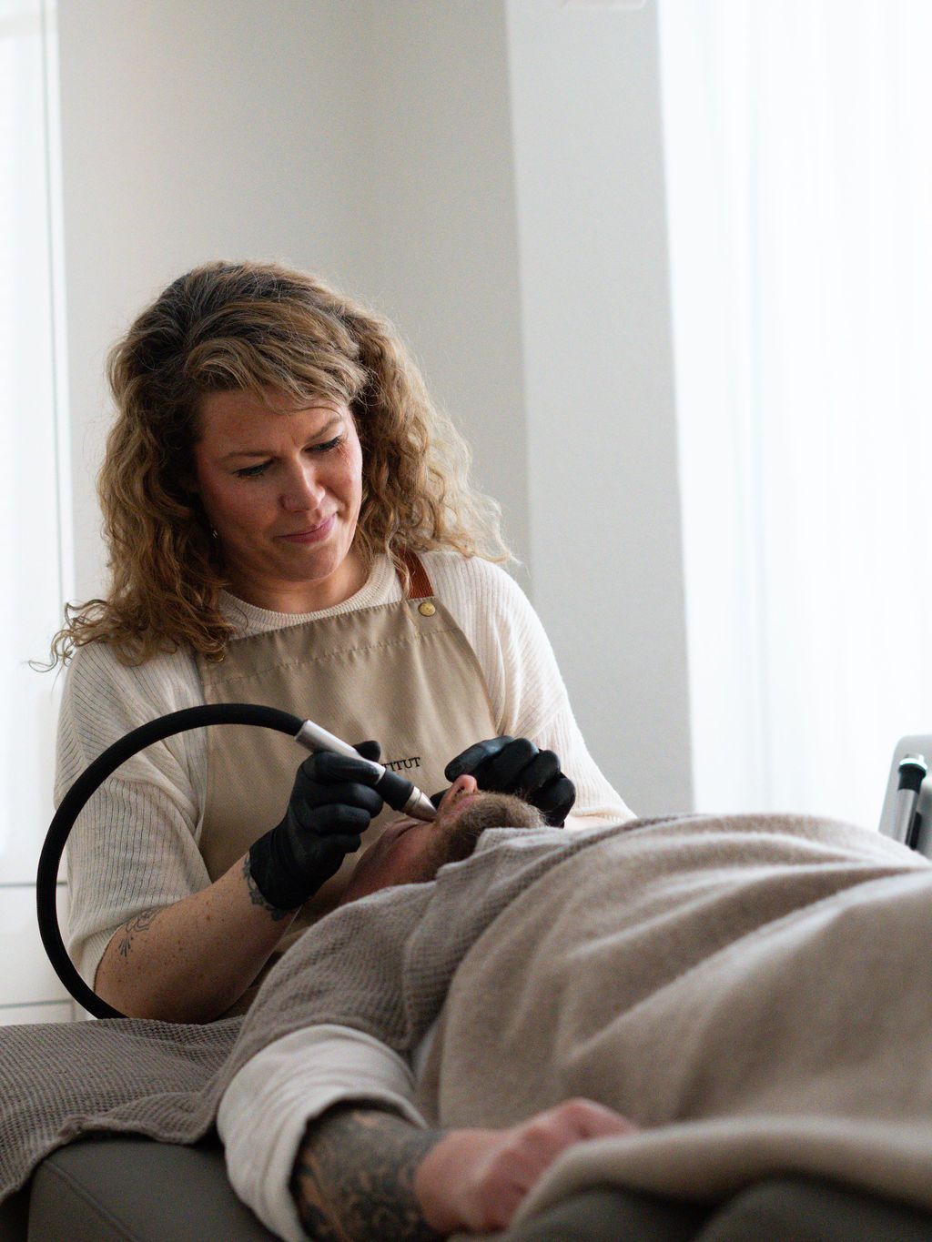 Eine Frau benutzt in einem Salon eine Maschine im Gesicht eines Mannes.