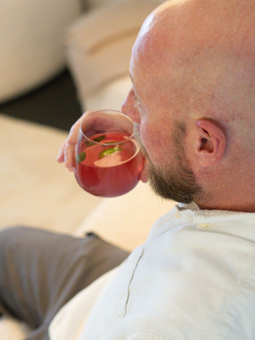 Ein Mann mit Bart trinkt ein Glas rote Flüssigkeit.