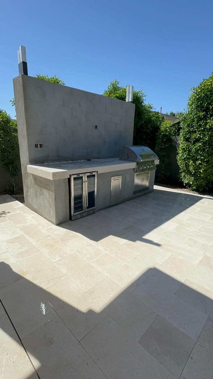 A patio with a concrete wall and a stainless steel grill.