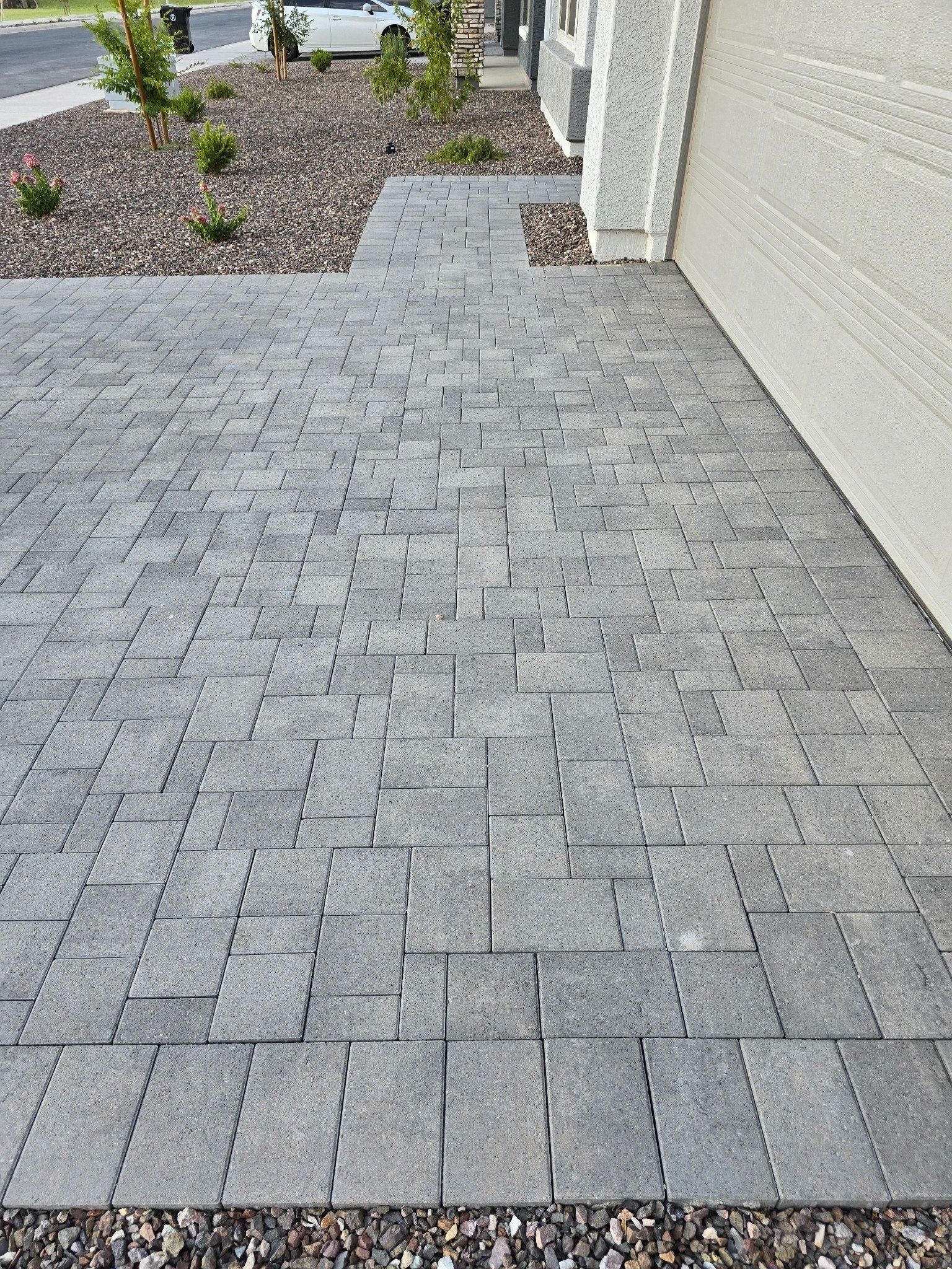 A brick walkway leading to a garage next to a house.
