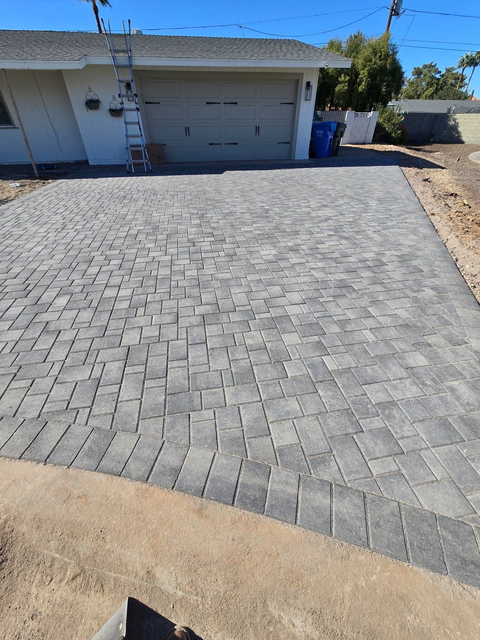 A brick driveway is being built in front of a house.