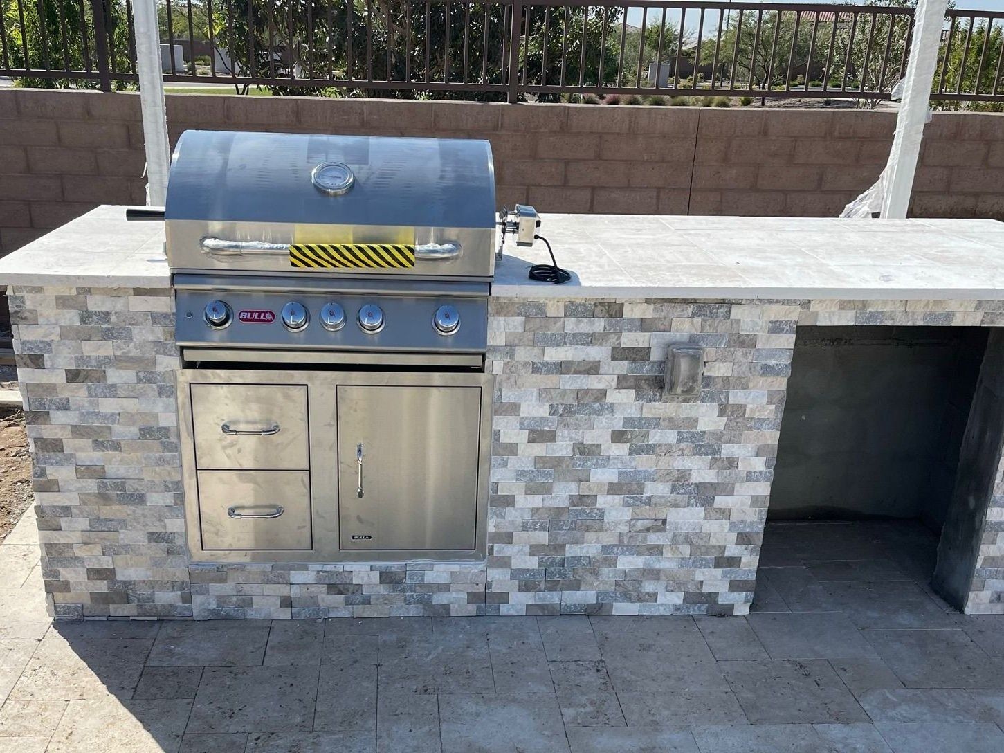 A stainless steel grill is sitting on top of a brick counter.