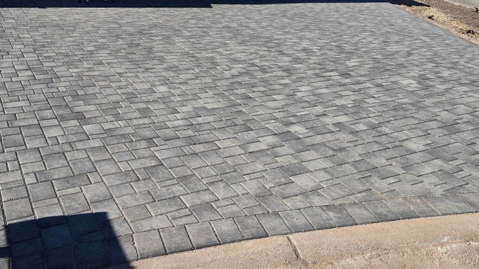 A close up of a brick driveway with a shadow on the ground.