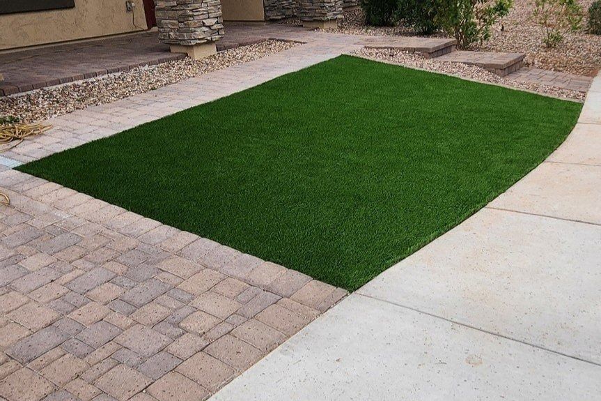 A large green turf installation is next to a sidewalk.
