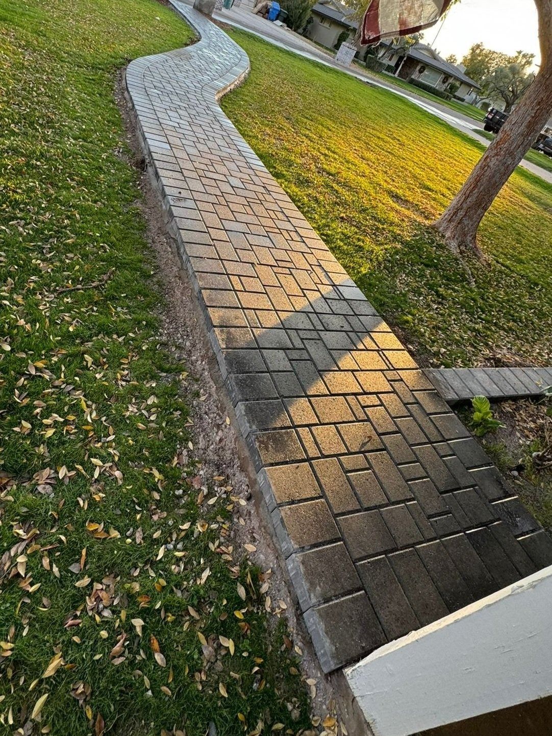 A brick walkway going through a lush green field.