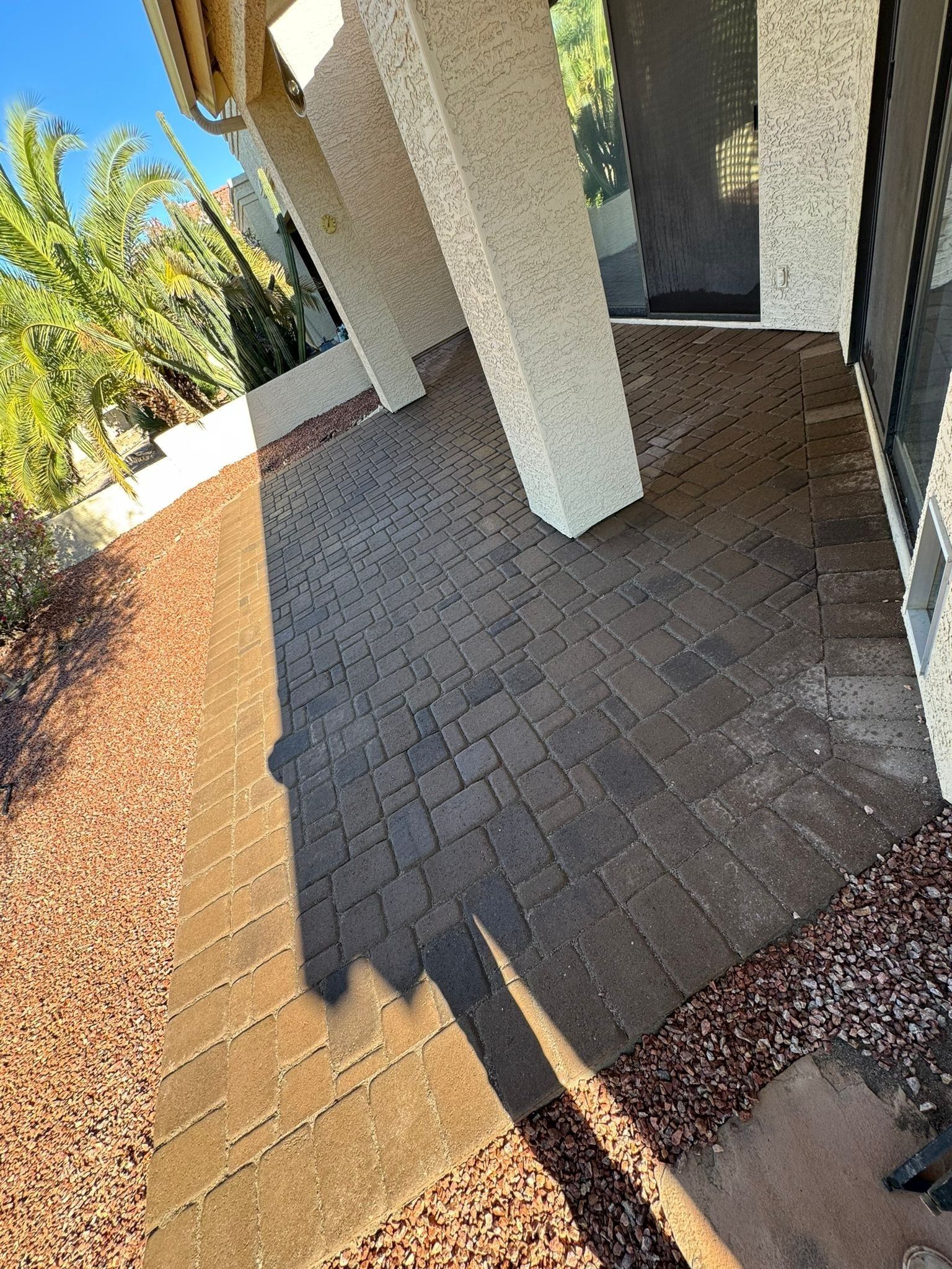 A patio with bricks and gravel in front of a house.