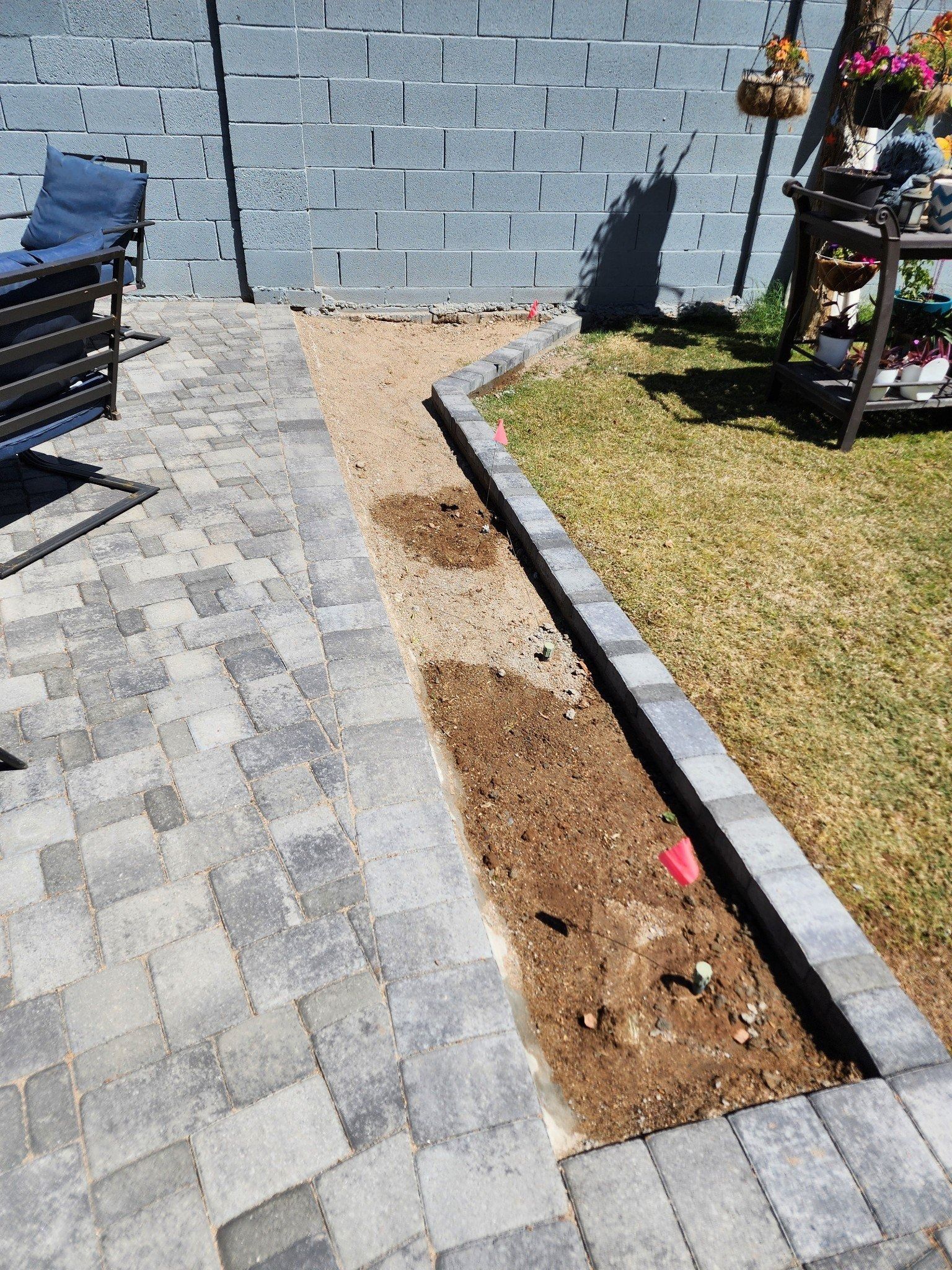 A patio with a bench and a brick wall in the background.