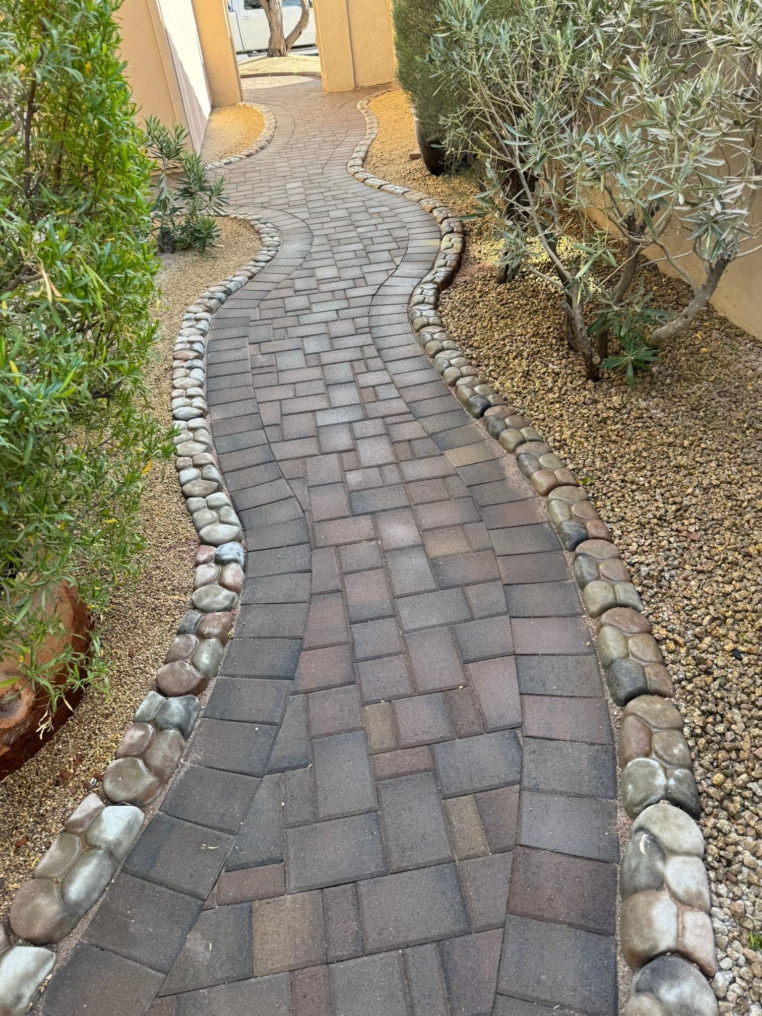 A brick walkway surrounded by rocks and trees in a garden.